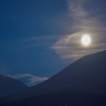 Lysende måne mellom mørke fjell